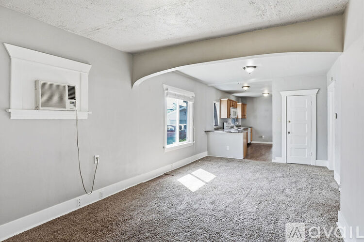 A spacious room with a window, a desk, and a carpeted floor.