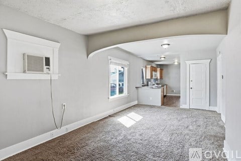 A spacious room with a window, a desk, and a carpeted floor.