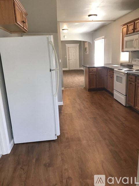 A kitchen with a white refrigerator and wooden floors.
