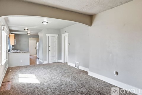 A spacious living room with a carpeted floor and white walls.