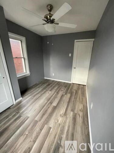 A room with a ceiling fan and wooden flooring.