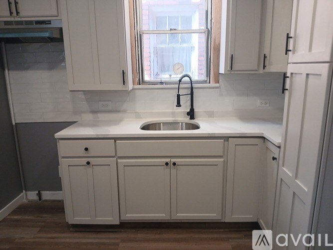 A kitchen with white cabinets and a window.