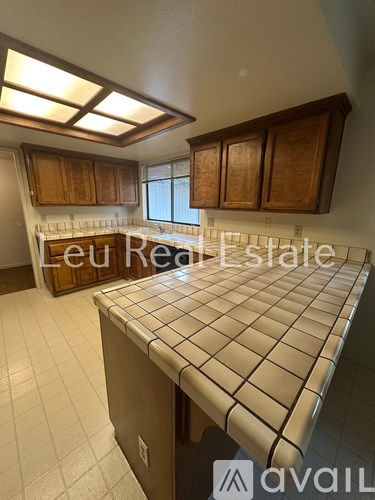A kitchen with a tile counter top and wooden cabinets.