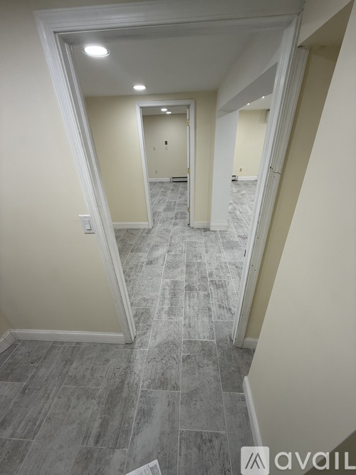 A hallway with a tiled floor and white walls.