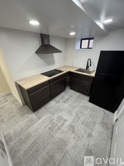 A kitchen with a black refrigerator, a sink, and a window.