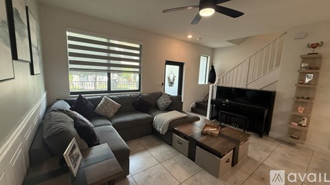 A living room with a grey couch and a black piano.