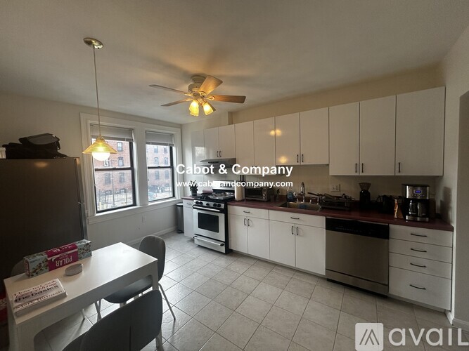 A kitchen with white cabinets and a black refrigerator.