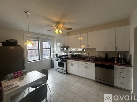 A kitchen with white cabinets and a black refrigerator.