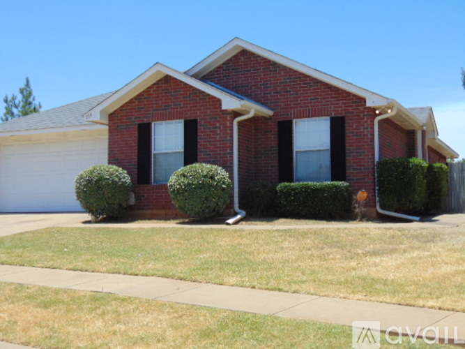 A red brick house with a white garage door and black shutters.