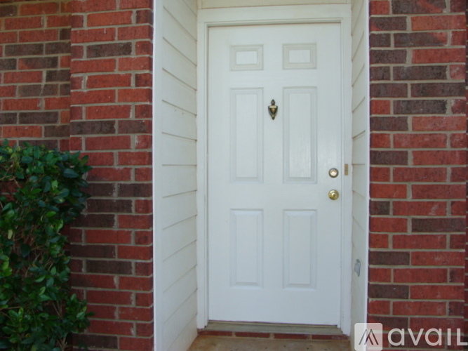 A white door with a gold handle is set in a brick wall.