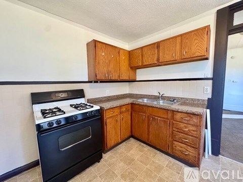 A kitchen with a black stove and wooden cabinets.