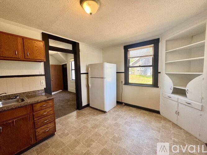 A kitchen with a sink, refrigerator, and cabinets.