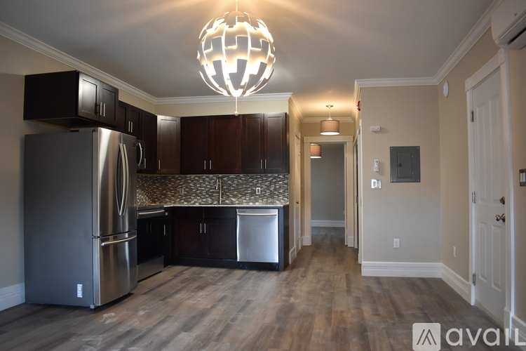A kitchen with a refrigerator, cabinets, and a chandelier.