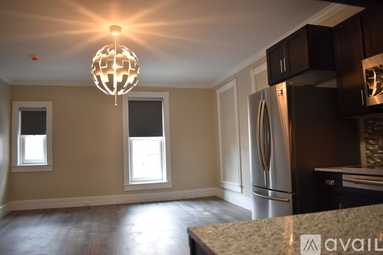A kitchen with a refrigerator, cabinets, and a chandelier.