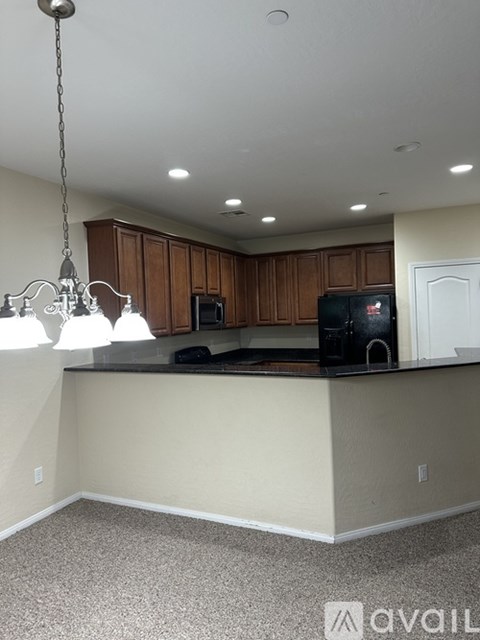 A kitchen with wooden cabinets and a black microwave.