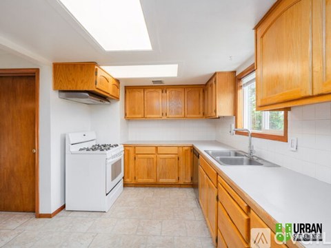 A kitchen with wooden cabinets and a white stove top oven.