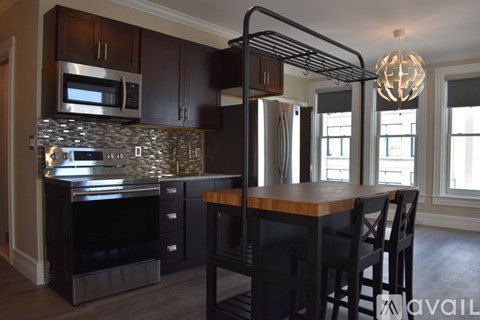 A kitchen with dark wood cabinets and a stone backsplash.