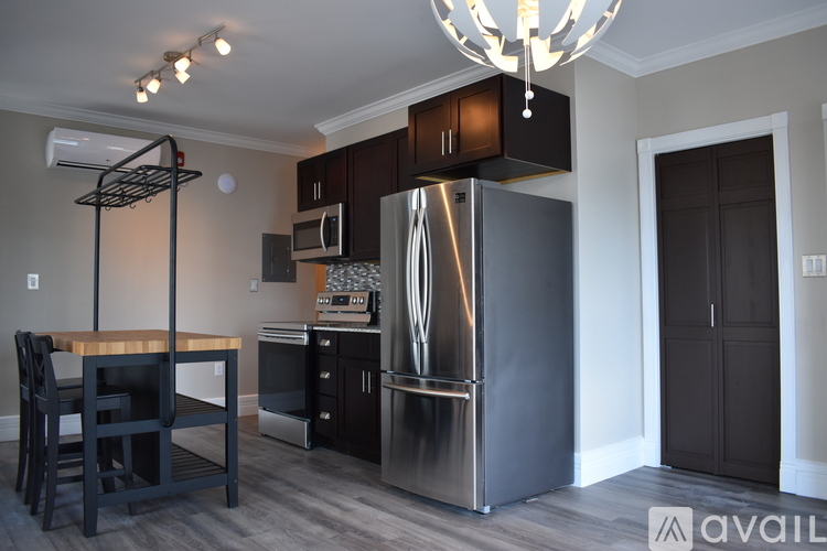 A kitchen with a refrigerator, microwave, oven, and a dining table with chairs.