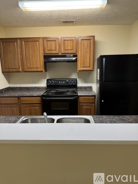 A kitchen with wooden cabinets and a black refrigerator.