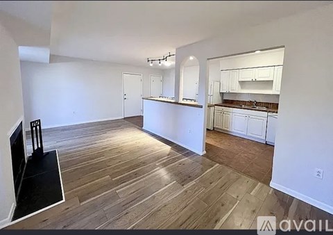 A living room with a television and a kitchen area in the background.