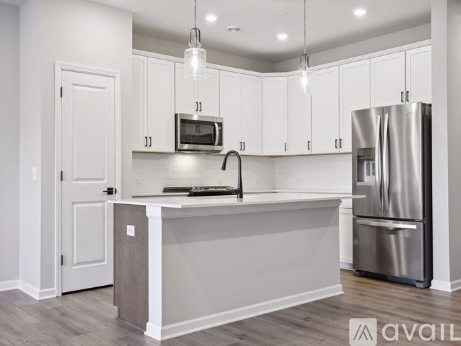 A kitchen with white cabinets and a stainless steel refrigerator.