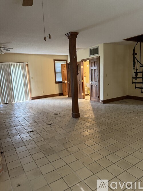 A spacious room with a tiled floor and a staircase on the right side.