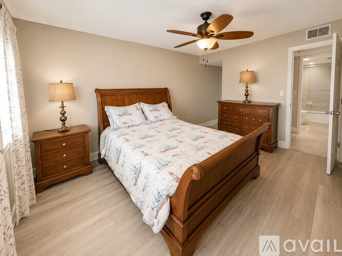 A bedroom with a large bed, a ceiling fan, and two lamps.