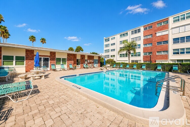 A large outdoor swimming pool surrounded by sun loungers and palm trees.