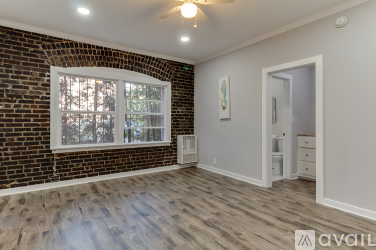 A room with a brick wall and wooden flooring is available for rent.