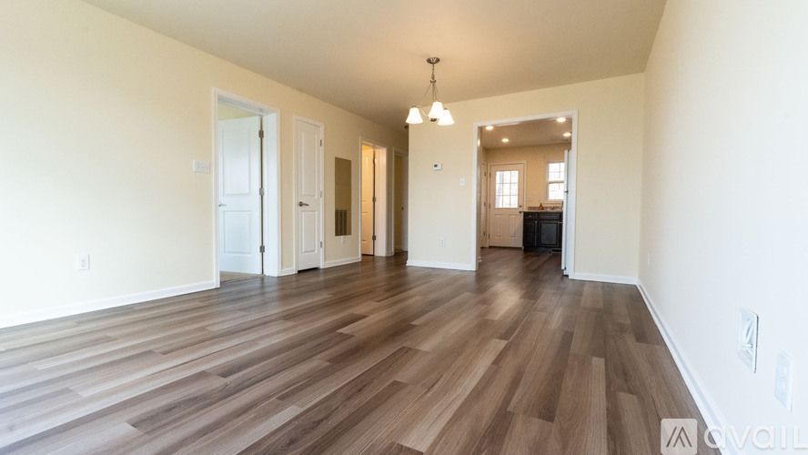 A spacious room with wooden flooring and white walls.