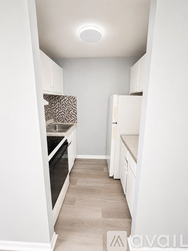 A kitchen with white cabinets and a light brown floor.