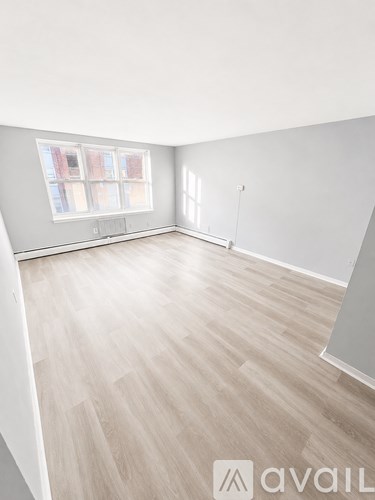 A room with wooden flooring and a large window.