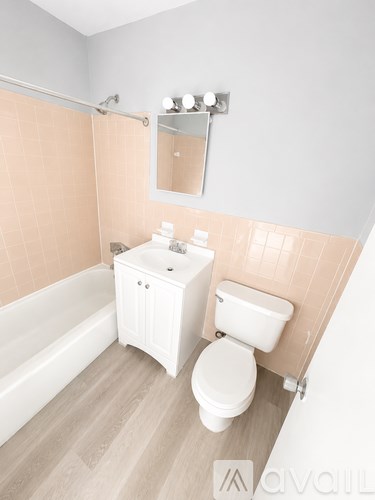 A white toilet and sink in a bathroom with a pink tiled wall.