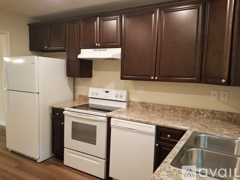 A kitchen with white appliances and brown cabinets.