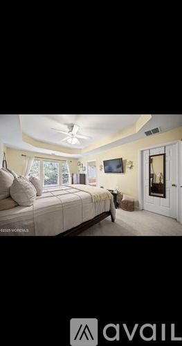A bedroom with a bed, a ceiling fan, and a door.