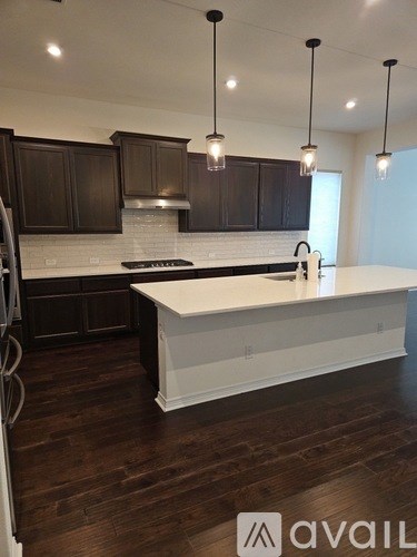 A kitchen with dark brown cabinets and a white island.