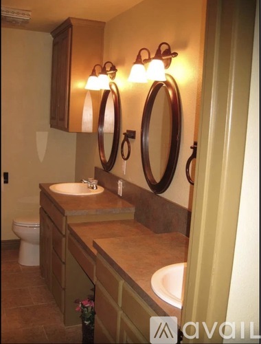 A bathroom with a toilet, sink, and mirrors.