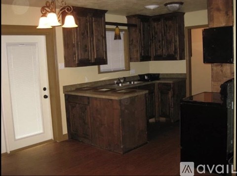 A kitchen with wooden cabinets and a black counter.