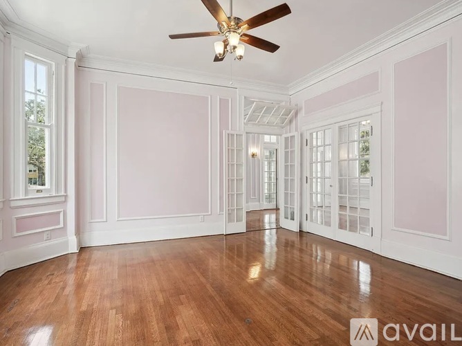 A spacious room with a ceiling fan and wooden flooring.