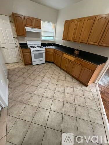 A kitchen with brown cabinets and a white stove top oven.