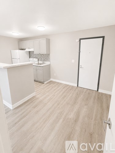 A kitchen with white appliances and cabinets with a white door to the right.