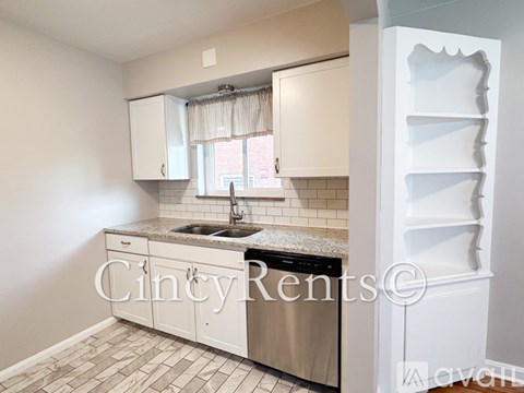 A kitchen with white cabinets and a tiled floor.