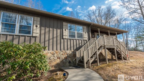 A house with a wooden deck and a stone wall.