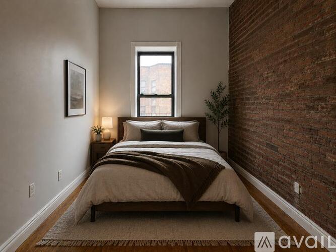 A bedroom with a brick wall and a bed with a brown comforter.