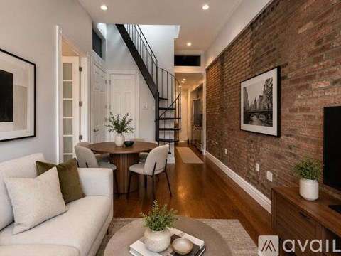 A living room with a white couch and a brick wall.