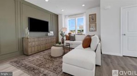 A living room with a white couch and a flat screen TV mounted on the wall.
