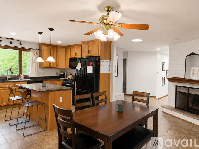 A kitchen with a table and chairs in the foreground and a fireplace in the background.