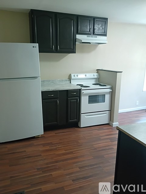 A kitchen with a white fridge and a white stove with black cabinets.
