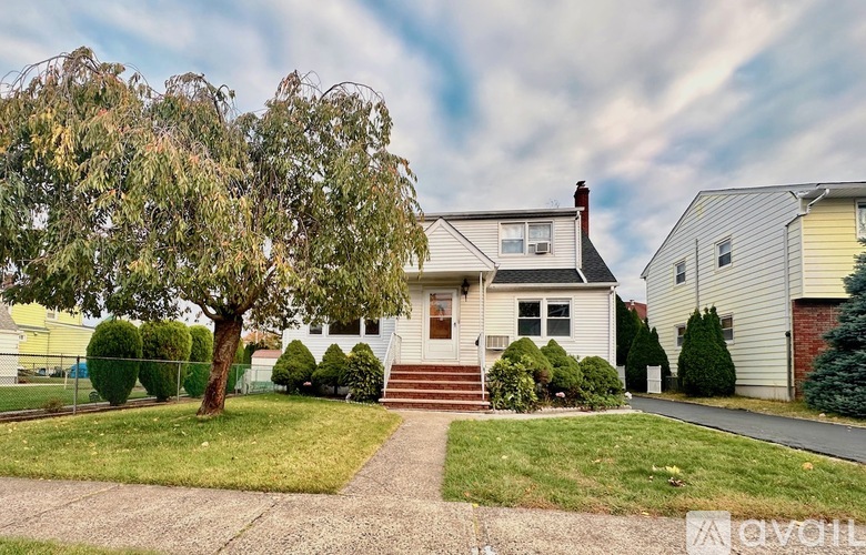 A house with a white exterior and a tree in front.