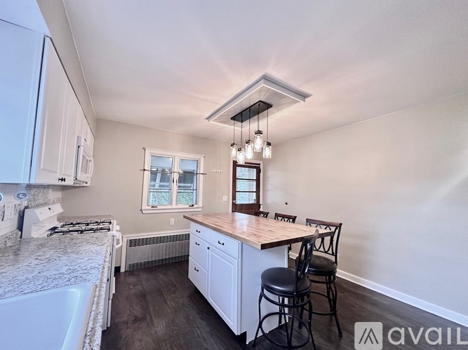 A kitchen with white cabinets and a wooden island.
